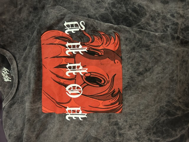 Photo of a grey T Shirt with a red anime drawing of a girl looking at the viewer. Text reading 'Poppy' in medieval style font is above it.
